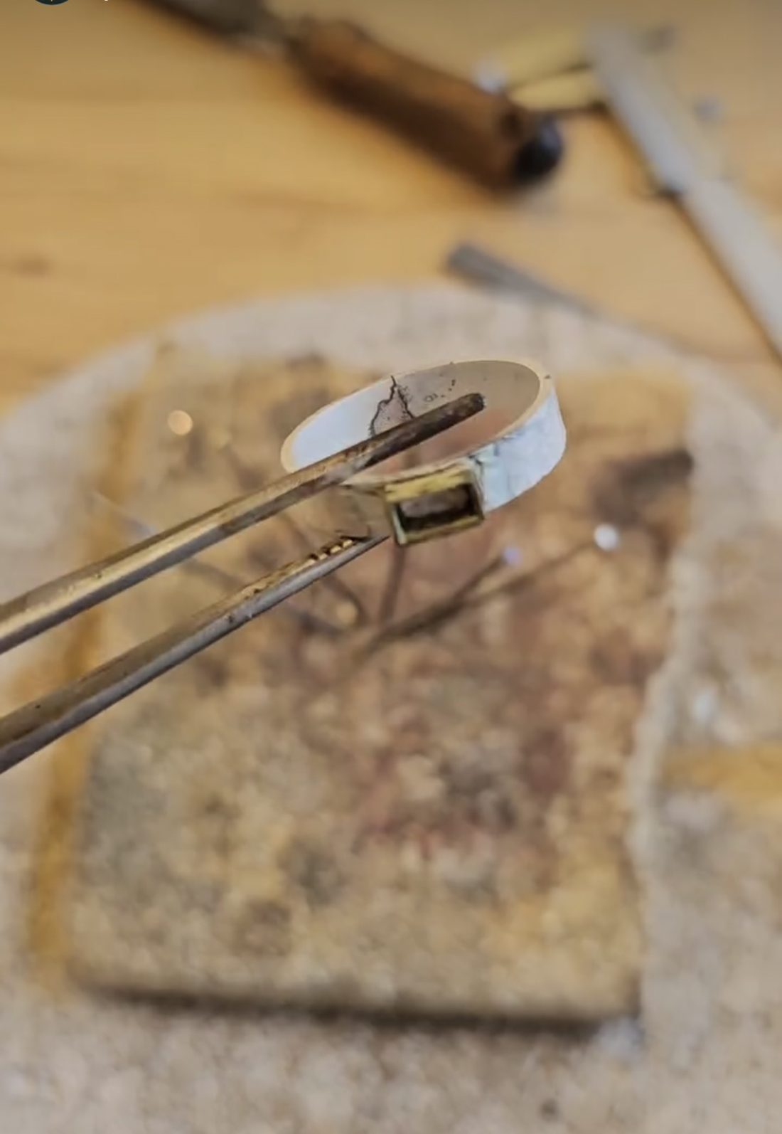 Zilveren ring met een rechthoekige zetting, vastgehouden met een pincet